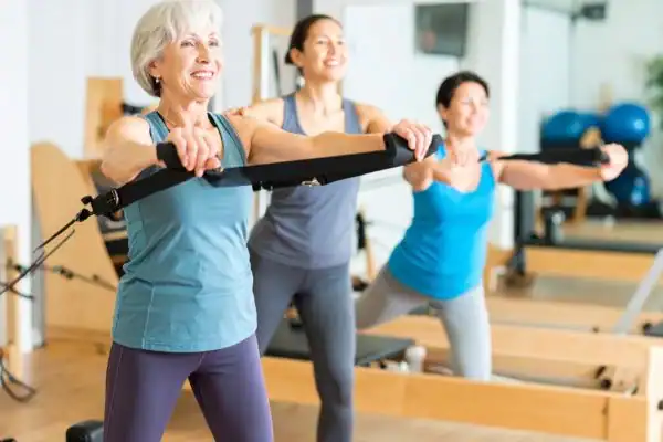 Toning Arms After 60: Empowering Womens Fitness Through Effective Weight Training 2 older woman doing weight training Kingswinford and resistance in the gym to tone upper arms