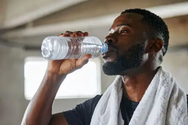 Image of man drinking water to improve hydration Kingswinford after work out.